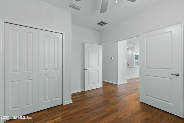 unfurnished bedroom featuring dark wood-type flooring, ceiling fan, and a closet