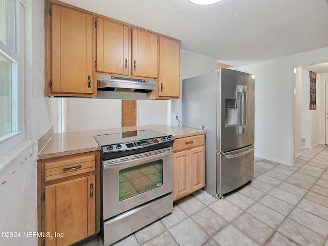 kitchen featuring a textured ceiling, stainless steel appliances, and light tile patterned floors