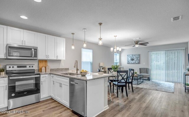 kitchen featuring stainless steel appliances, white cabinetry, kitchen peninsula, and light wood-type flooring