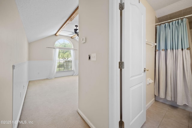 96316 Ridgewood Cir, Fernandina Beach, FL 32034 - hall with vaulted ceiling, a textured ceiling, tile patterned flooring, and wainscoting