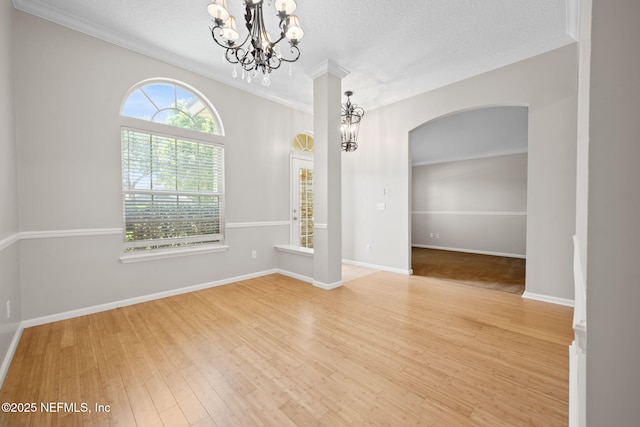96316 Ridgewood Cir, Fernandina Beach, FL 32034 - spare room with a chandelier, arched walkways, wood finished floors, ornamental molding, and a textured ceiling