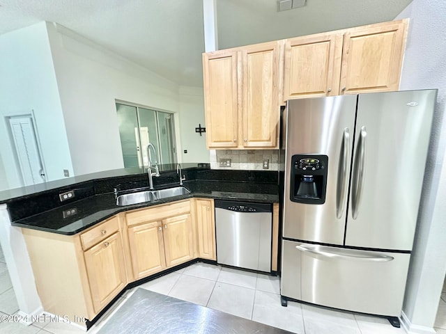 kitchen with dark stone counters, stainless steel appliances, sink, light brown cabinets, and light tile patterned flooring