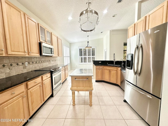 kitchen with backsplash, vaulted ceiling, appliances with stainless steel finishes, decorative light fixtures, and light tile patterned flooring