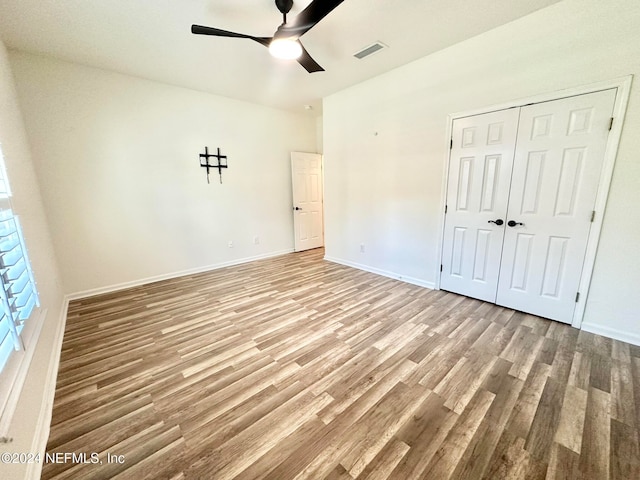 unfurnished bedroom featuring ceiling fan, light hardwood / wood-style floors, and a closet