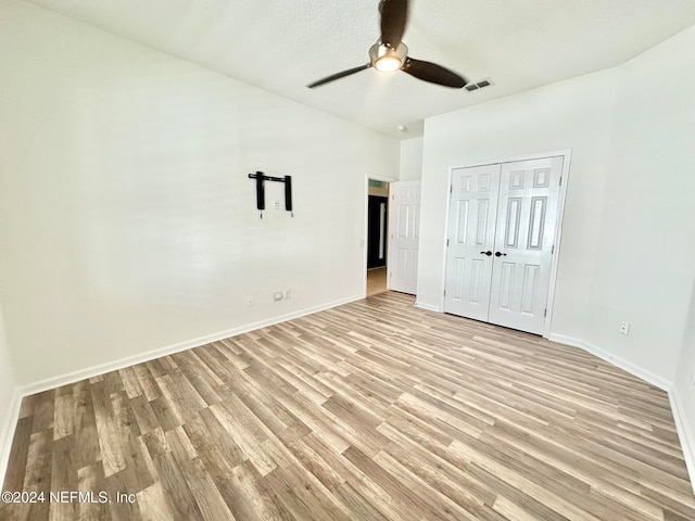 unfurnished bedroom with ceiling fan, a closet, a textured ceiling, and light hardwood / wood-style flooring