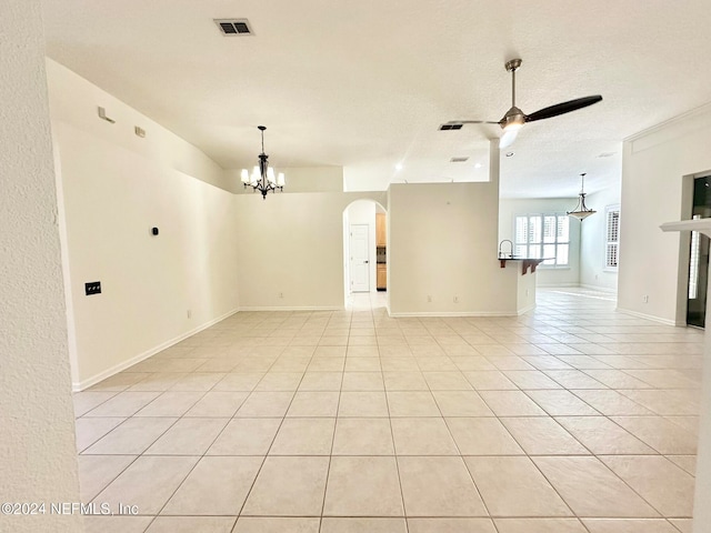 tiled empty room with a textured ceiling, ceiling fan with notable chandelier, and sink