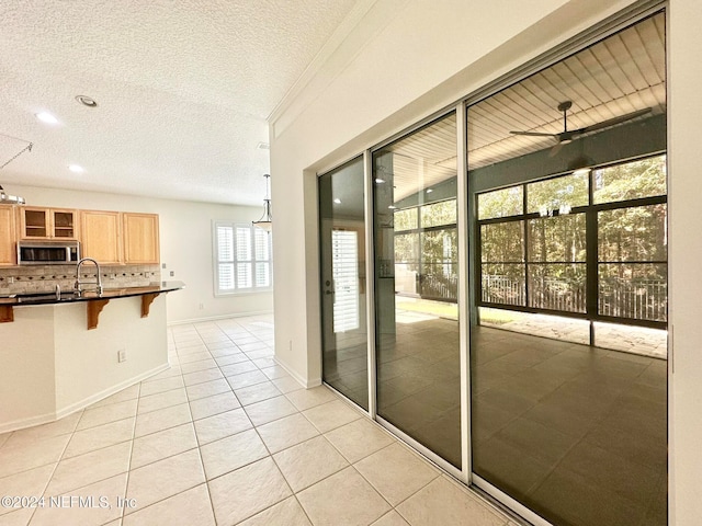 interior space featuring ceiling fan, light tile patterned flooring, and a textured ceiling