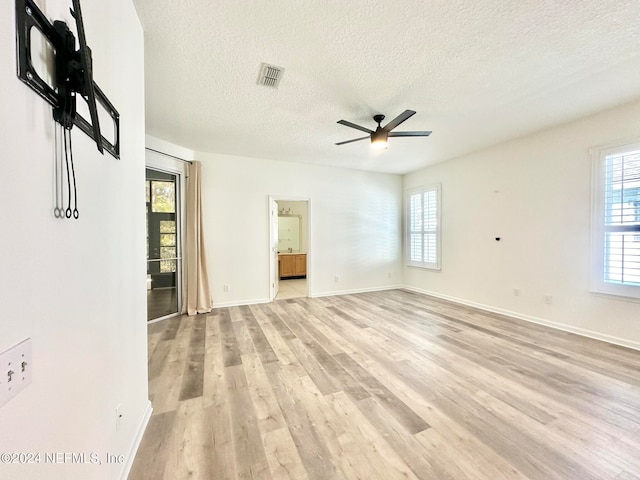 spare room featuring ceiling fan, light wood-type flooring, and a textured ceiling