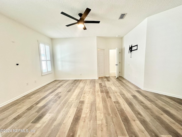 spare room with ceiling fan, light hardwood / wood-style floors, and a textured ceiling