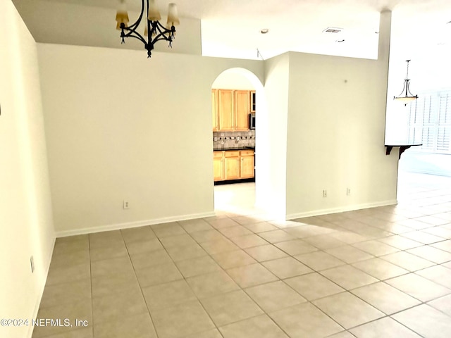 unfurnished room featuring light tile patterned floors and a notable chandelier