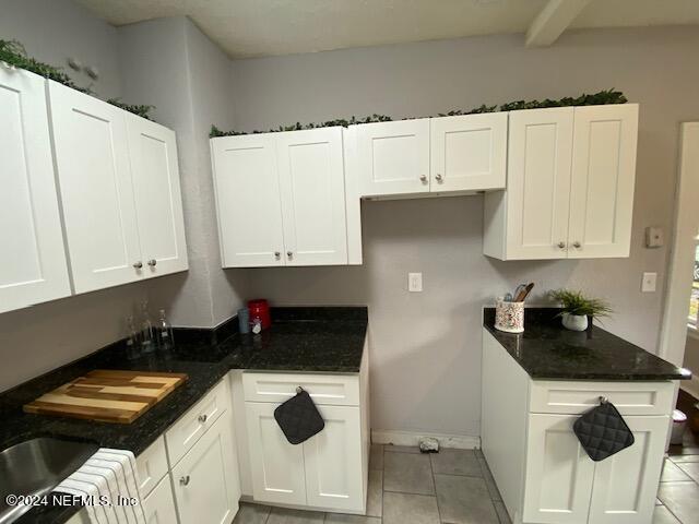 kitchen with white cabinets, dark stone countertops, and light tile patterned floors