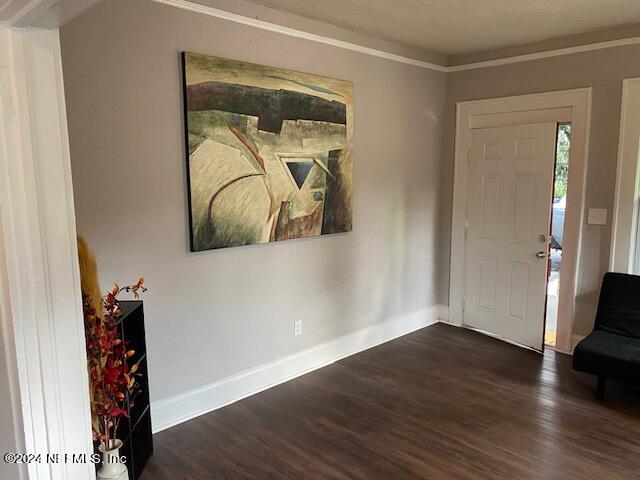 entrance foyer with a textured ceiling, dark hardwood / wood-style floors, and crown molding