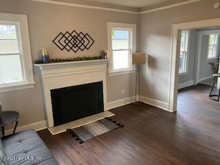 living room with dark wood-type flooring and crown molding