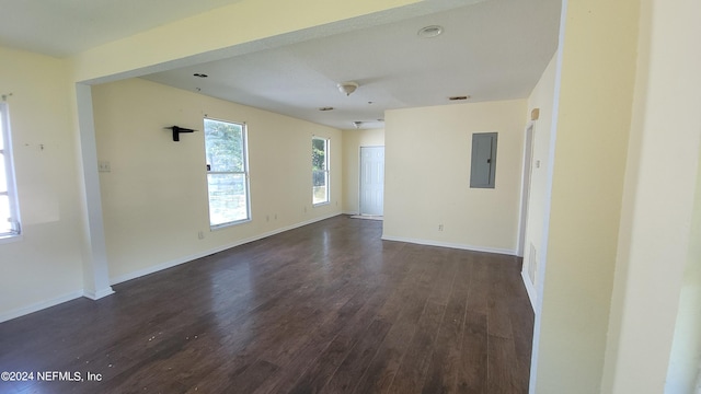 spare room with electric panel and dark wood-type flooring