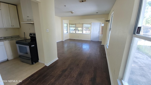 kitchen featuring wood-type flooring, white cabinets, and stove