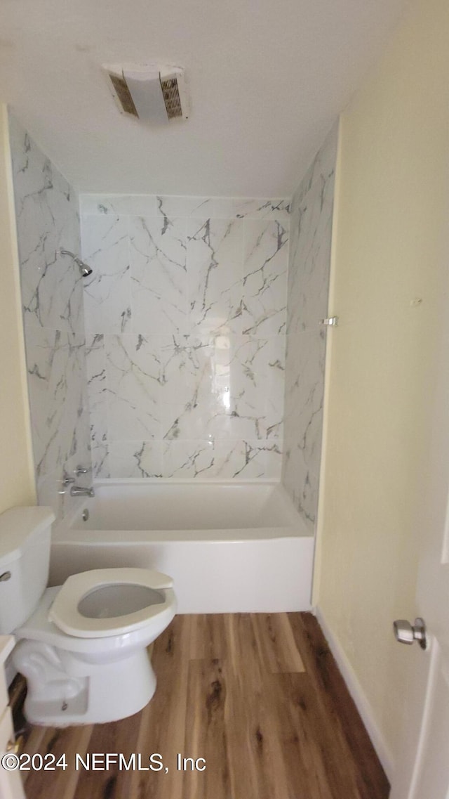 bathroom with tiled shower / bath combo, toilet, and wood-type flooring