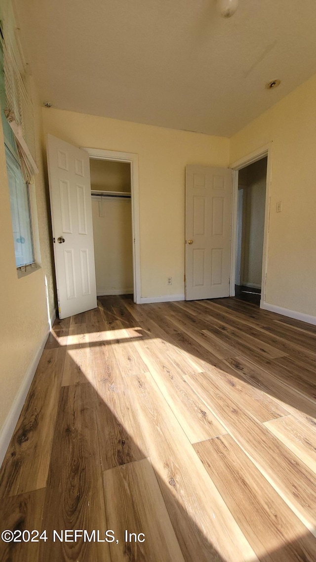 unfurnished bedroom featuring a closet and hardwood / wood-style floors