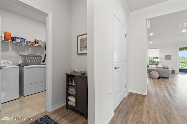 clothes washing area with washer and dryer, ornamental molding, and light hardwood / wood-style flooring