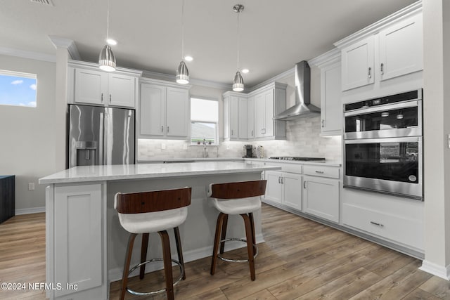 kitchen with white cabinetry, appliances with stainless steel finishes, and wall chimney range hood