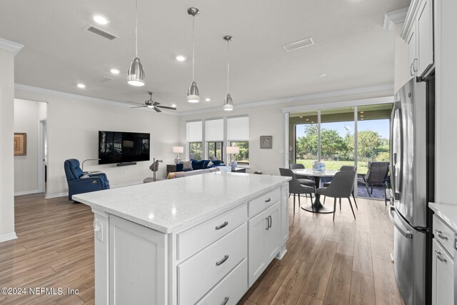 kitchen featuring light wood-type flooring, white cabinetry, a kitchen island, ceiling fan, and stainless steel fridge