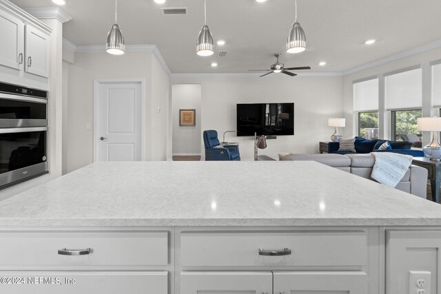 kitchen featuring white cabinets, decorative light fixtures, ornamental molding, ceiling fan, and double oven