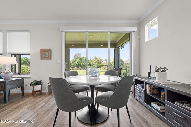 dining space with light hardwood / wood-style flooring and ornamental molding