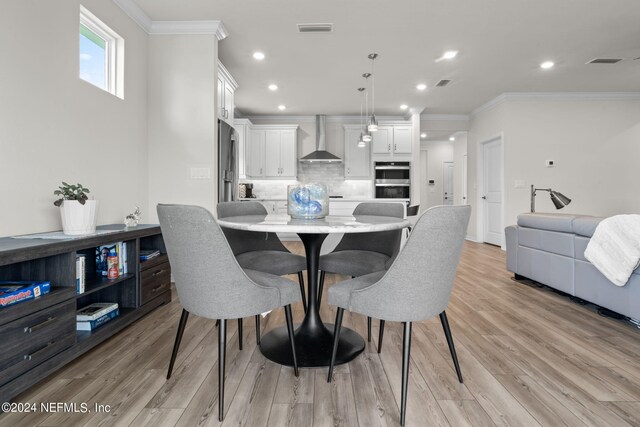 dining area featuring light wood-type flooring and ornamental molding