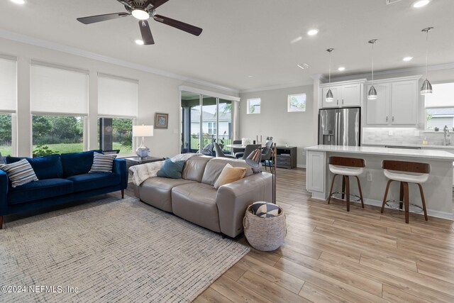 living room featuring ceiling fan, light hardwood / wood-style floors, a healthy amount of sunlight, and crown molding