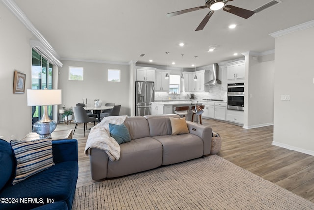 living room featuring light hardwood / wood-style floors, ceiling fan, and crown molding