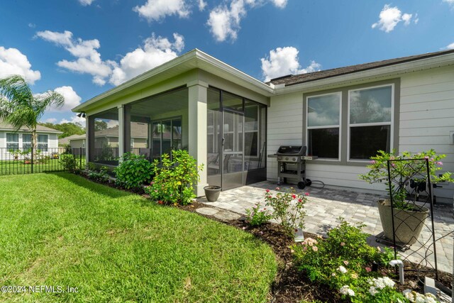 back of house featuring a lawn, a sunroom, and a patio area