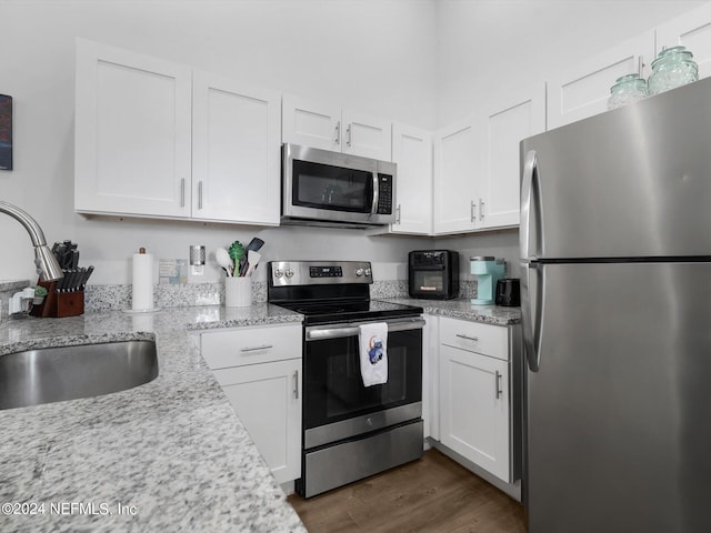 2745 Gilmore St, Jacksonville, FL 32205 - kitchen with a sink, dark wood-type flooring, light stone countertops, appliances with stainless steel finishes, and white cabinetry