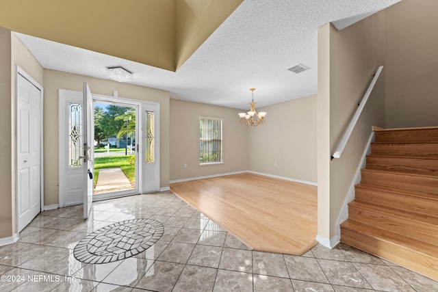 entrance foyer with light hardwood / wood-style floors, a textured ceiling, and a chandelier