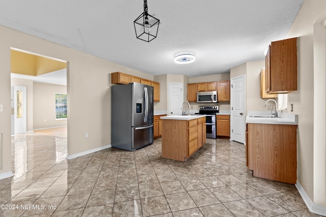 kitchen featuring an island with sink, hanging light fixtures, sink, a textured ceiling, and appliances with stainless steel finishes