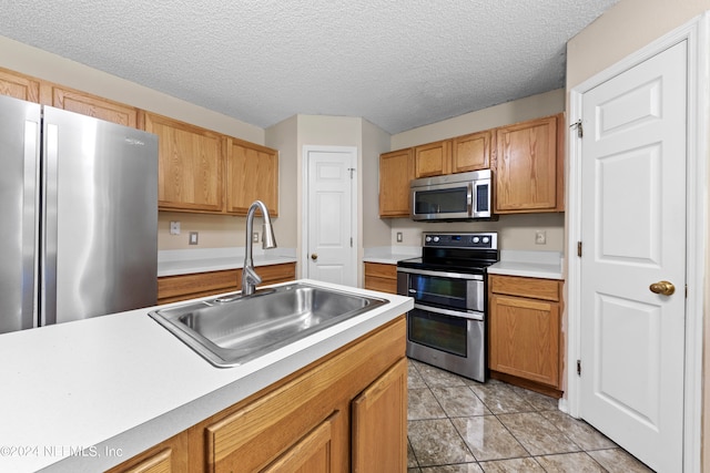 kitchen with stainless steel appliances, a textured ceiling, light tile patterned floors, and sink