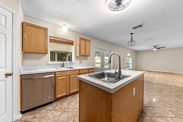 kitchen with ceiling fan, sink, a kitchen island with sink, and stainless steel dishwasher