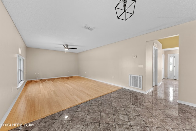 unfurnished room featuring wood-type flooring, ceiling fan, and a textured ceiling