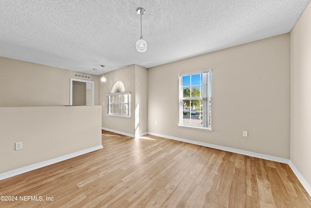 unfurnished room with a textured ceiling and light hardwood / wood-style flooring