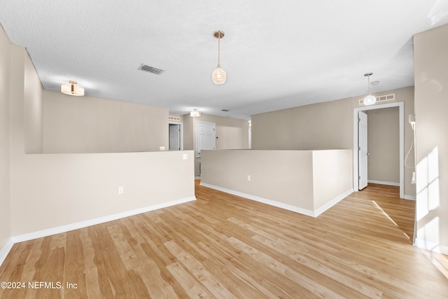 spare room featuring a textured ceiling and light hardwood / wood-style flooring