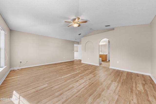 unfurnished living room featuring ceiling fan, vaulted ceiling, a textured ceiling, and light hardwood / wood-style floors