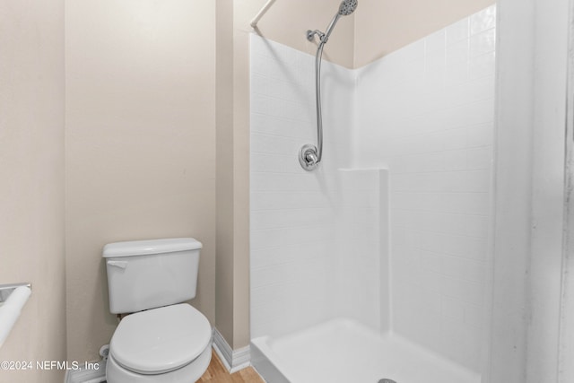 bathroom featuring a shower, hardwood / wood-style floors, and toilet