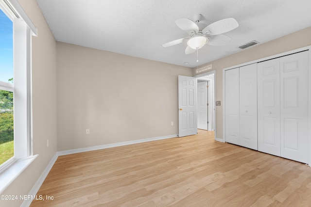 unfurnished bedroom with a textured ceiling, light hardwood / wood-style floors, ceiling fan, and a closet