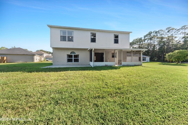 back of property with a sunroom, a patio, and a lawn