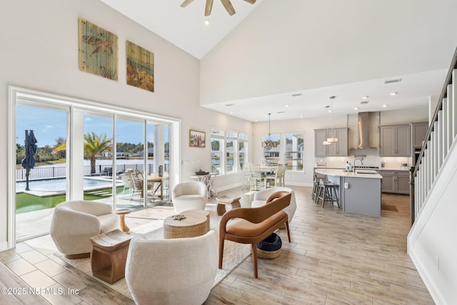 living room featuring wood finish floors, recessed lighting, a ceiling fan, high vaulted ceiling, and baseboards