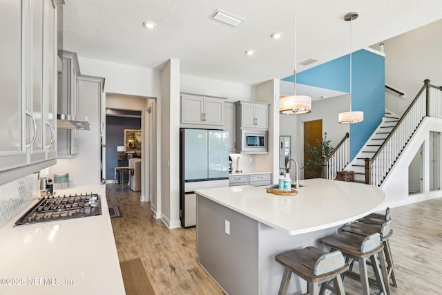 kitchen featuring appliances with stainless steel finishes, visible vents, a sink, and light wood finished floors