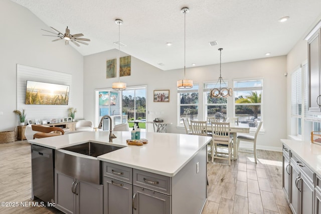 kitchen featuring gray cabinetry, a sink, visible vents, stainless steel dishwasher, and wood tiled floor