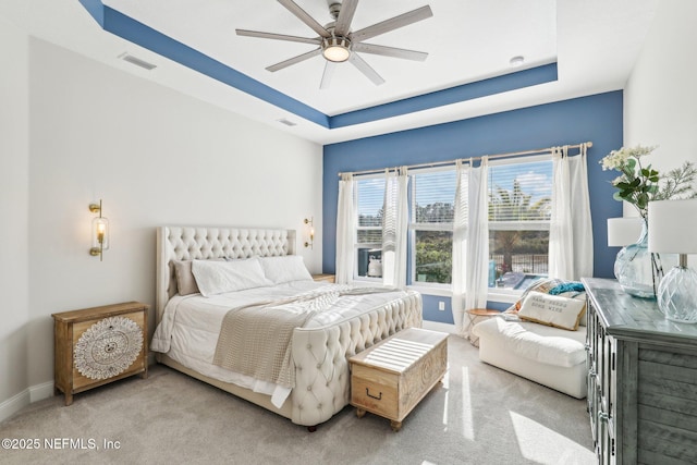 bedroom featuring a tray ceiling, baseboards, visible vents, and carpet