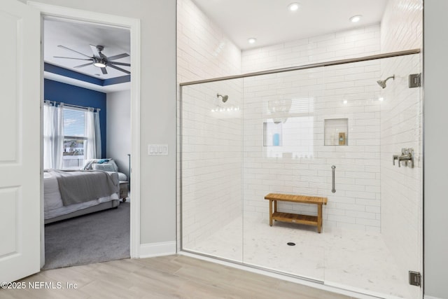 ensuite bathroom featuring a stall shower, baseboards, a ceiling fan, wood finished floors, and ensuite bathroom