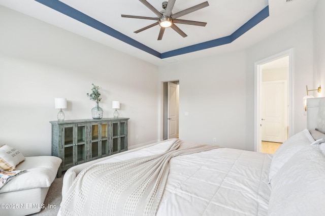 bedroom with a raised ceiling and ceiling fan