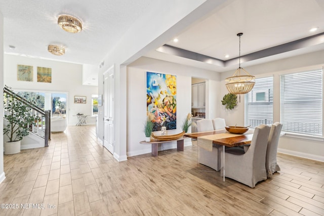 dining space featuring light wood-type flooring, plenty of natural light, stairway, and a notable chandelier