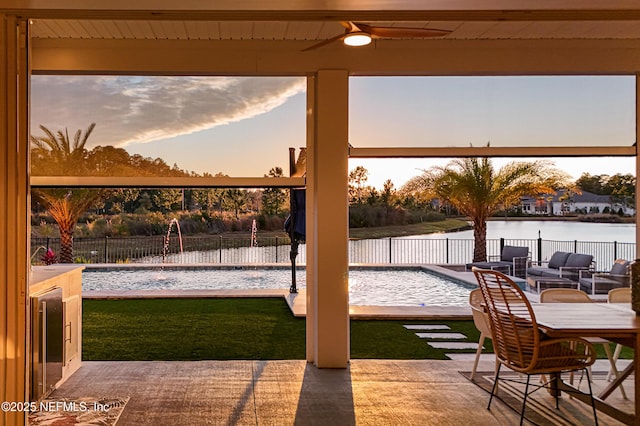 exterior space with ceiling fan, a fenced backyard, outdoor lounge area, a water view, and a lawn